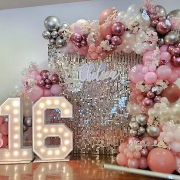 A pink and silver balloon arch with a sequin backdrop, light-up "16" numbers, and "Chelsea" sign.