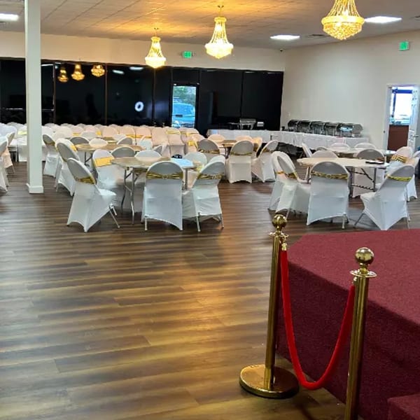 A large event hall with round tables and chairs, buffet stations, and chandeliers.
